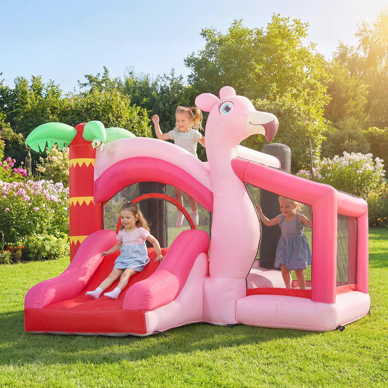 Three children playing on the pink flamingo bounce house in a garden
