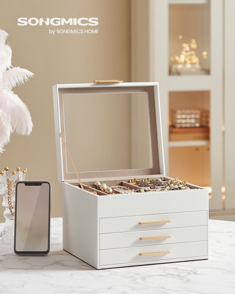 Open white jewellery box on a marble table beside a mobile phone showing its size