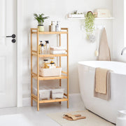 The bamboo shelving unit beside a bath, holding folded towels, bottles and a plant