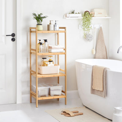 The bamboo shelving unit beside a bath, holding folded towels, bottles and a plant