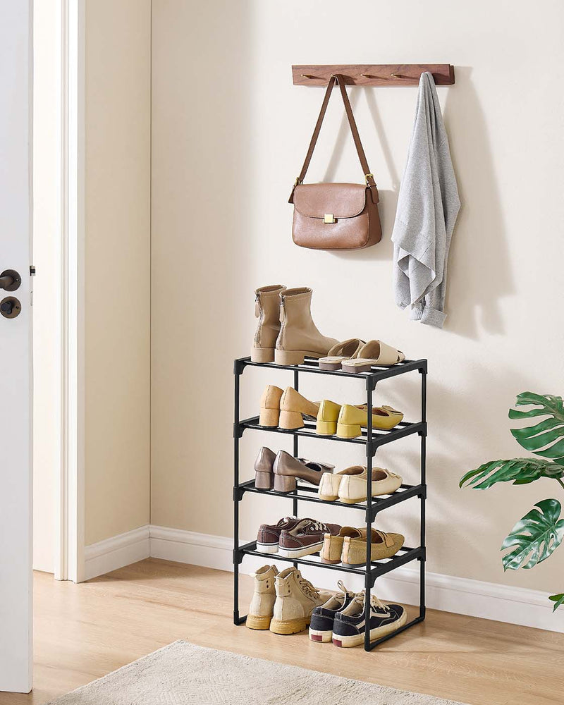 Black 4-tier shoe rack in a hallway corner below a wall hook with a bag and towel