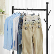 Pants hangers holding jeans and trousers on a clothes rail next to shirts on regular hangers