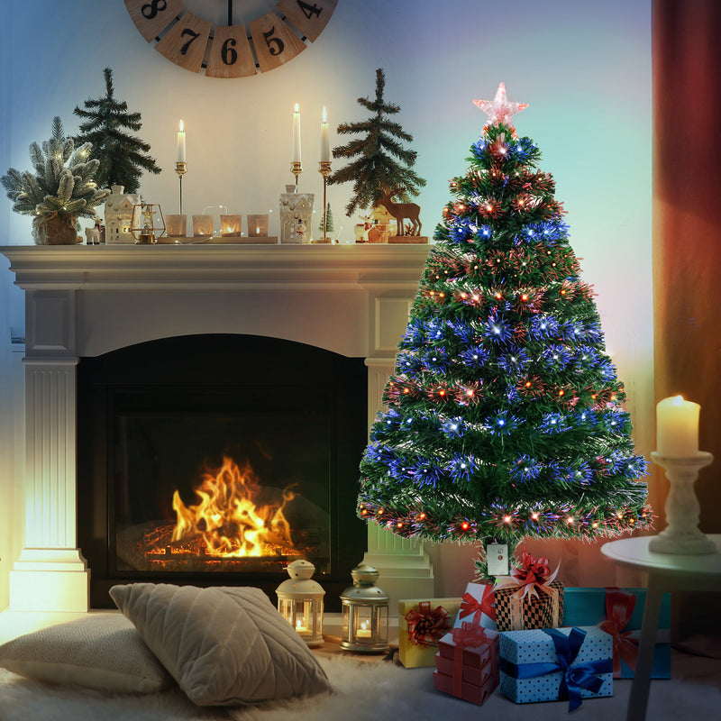 Lit tree beside a fireplace with candles and gifts
