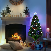 Tree glowing beside a fireplace with gifts and candles