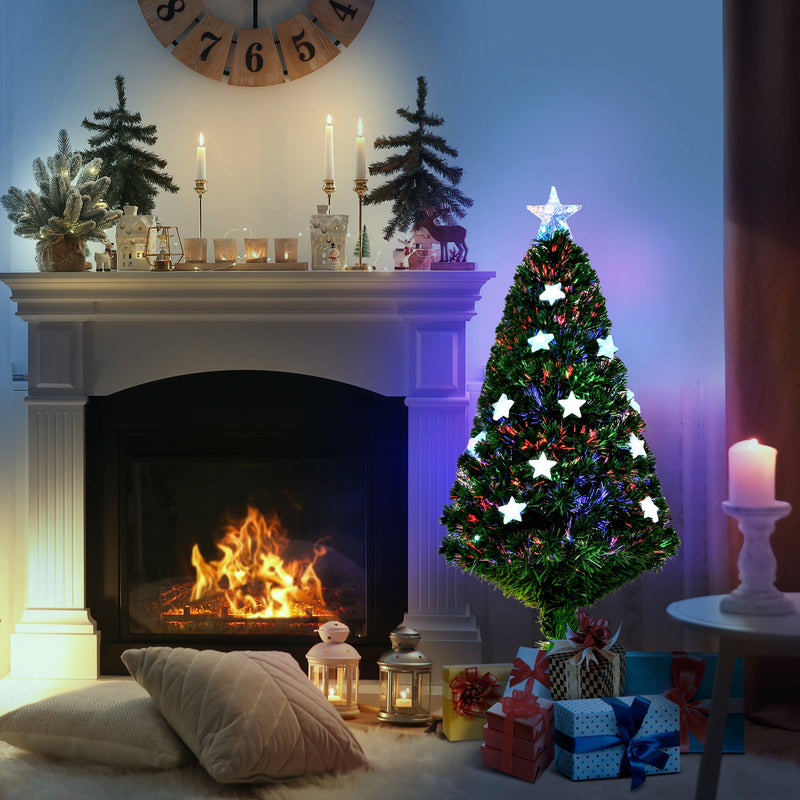 Tree glowing beside a fireplace with gifts and candles
