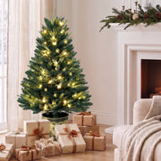 Pre-lit 4ft Christmas tree in a living room beside a fireplace with wrapped gifts around the pot
