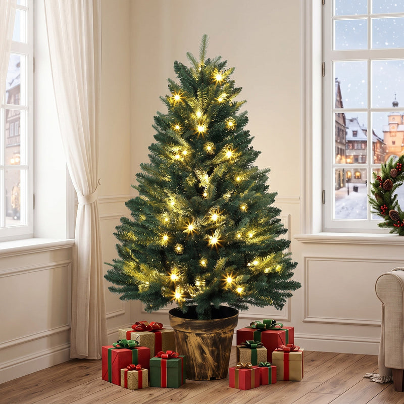 Lit Christmas tree in a bright room with red and green gifts around the pot base