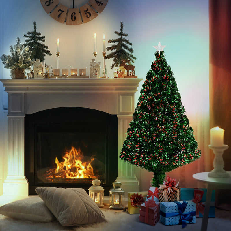 Lit fibre optic Christmas tree in front of a fireplace beside wrapped gifts