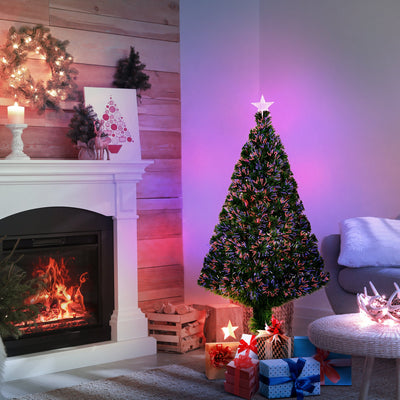 Lit fibre optic Christmas tree beside a fireplace with a purple glow behind it