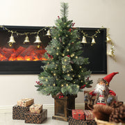 Pre-lit Christmas tree beside a fireplace with a Santa figure and wrapped gifts