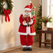 Santa figure beside a wreath, side table and Christmas greenery