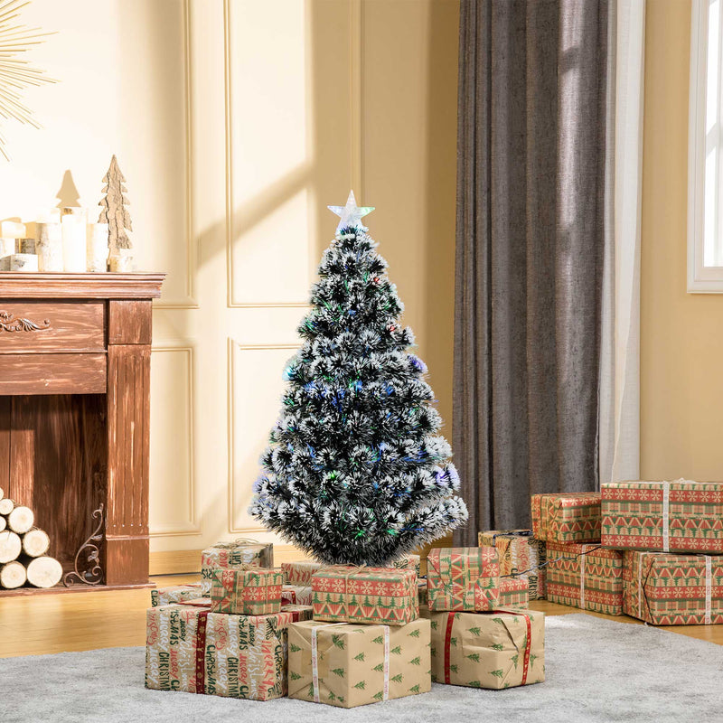 Tree in a room with a wooden fireplace and stacked gifts