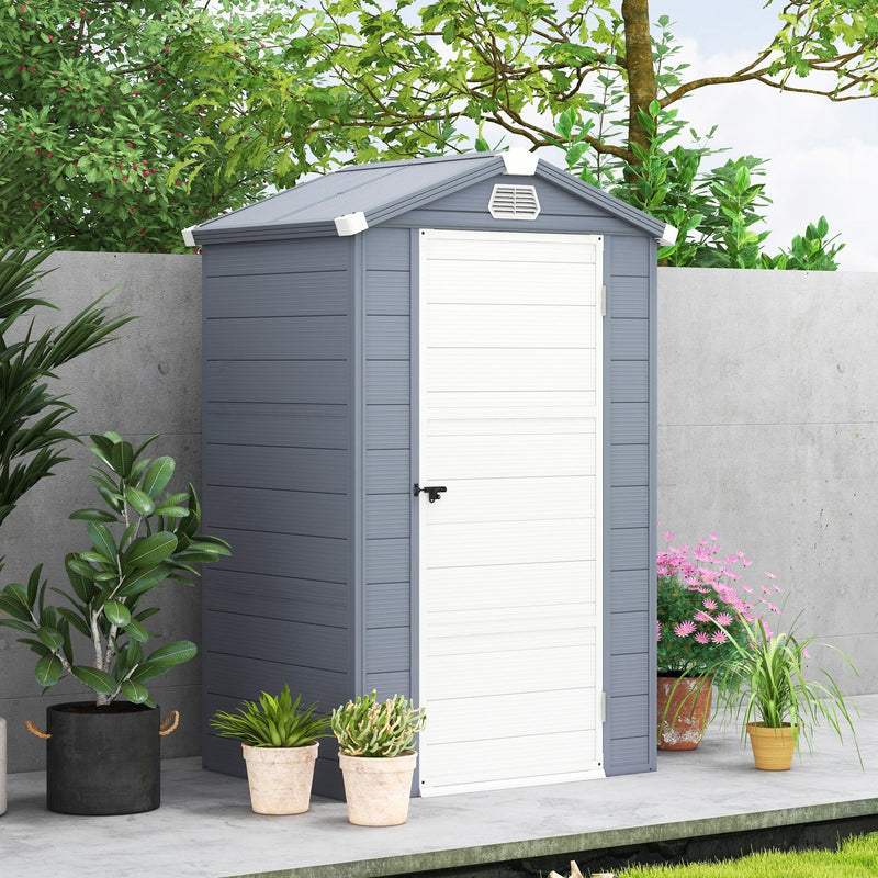 Grey plastic garden shed with the door shut, standing against a wall beside potted plants