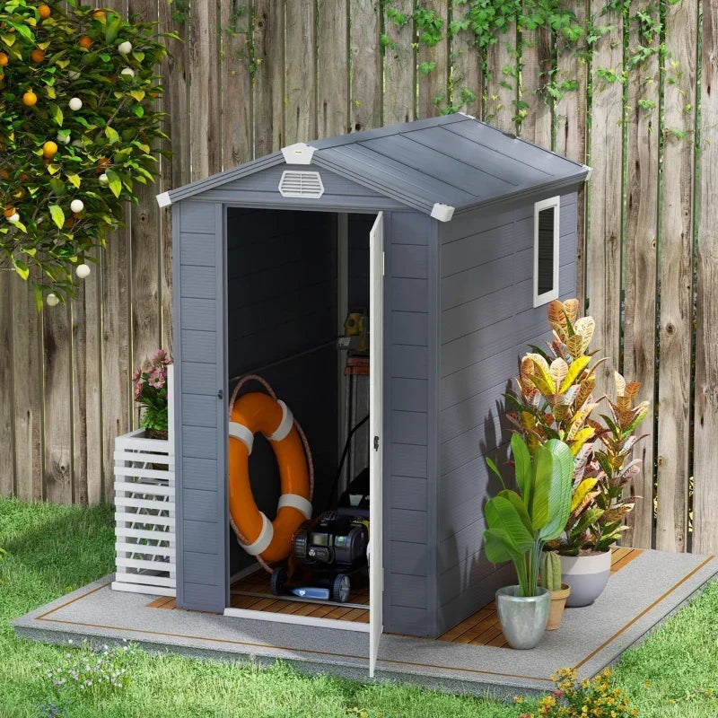 Plastic garden shed with the door open holding a life ring, hose and garden tools