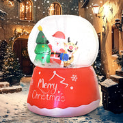 Lit snow globe inflatable on a snowy street outside a wooden door at night