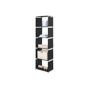 Slim black cube shelving unit holding a bag, towels, a woven basket and shoes