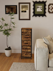Narrow chest of drawers in a living room beside a cream sofa and a wall of framed prints