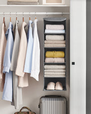 Grey hanging organiser at the end of a wardrobe rail holding folded jumpers, knitwear and slippers