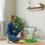 Lifestyle photo of a woman kneeling beside the green hamster cage at home