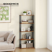 The shelf unit in a living room beside a cream sofa and framed floral print, holding books and decor