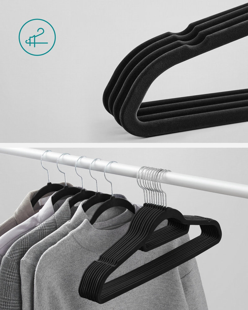 Close-up of stacked black velvet hangers next to hangers loaded with jumpers on a rail