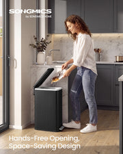 Woman in a grey kitchen tipping food scraps into the open black pedal bin