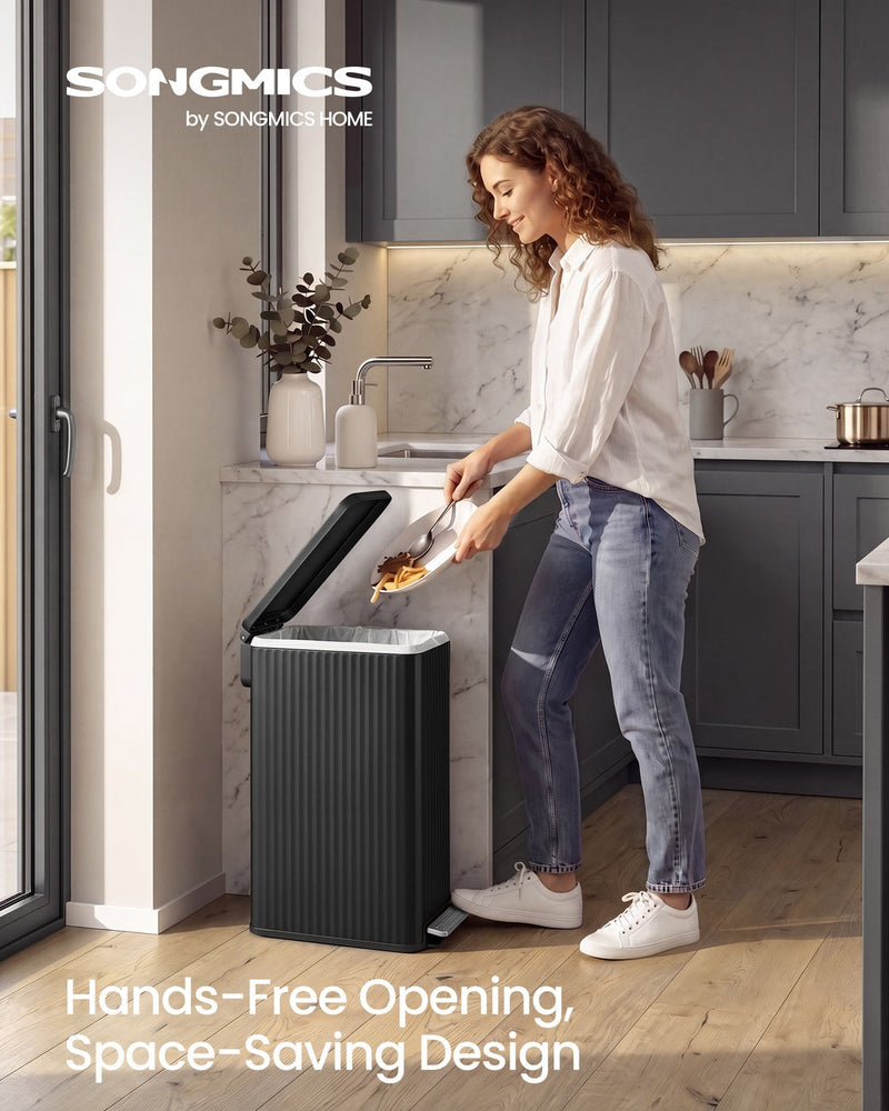 Woman in a grey kitchen tipping food scraps into the open black pedal bin