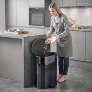 Woman scraping food into the open black pedal bin in a modern kitchen