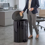 Man in an office dropping a cup into the open black pedal bin