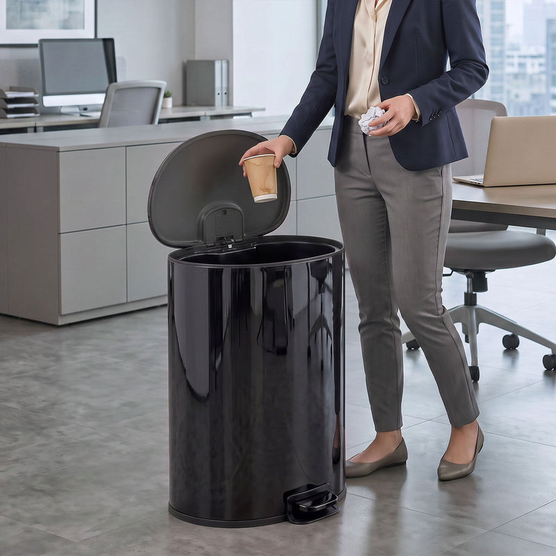 Man in an office dropping a cup into the open black pedal bin