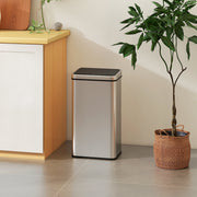 Silver sensor bin standing beside a kitchen cabinet and potted plant