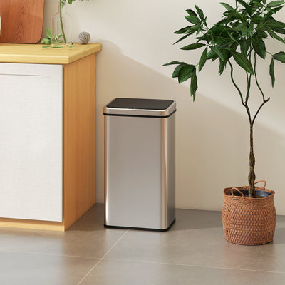 Silver sensor bin standing beside a kitchen cabinet and potted plant