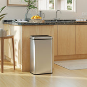 Silver sensor bin positioned beside a kitchen island with fresh fruit on the counter