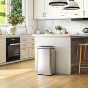 Silver sensor bin in a white and gold-accented kitchen beside an oven and bar stools