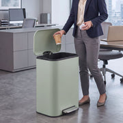 Woman in an office dropping a cup into an open light green 50L pedal bin