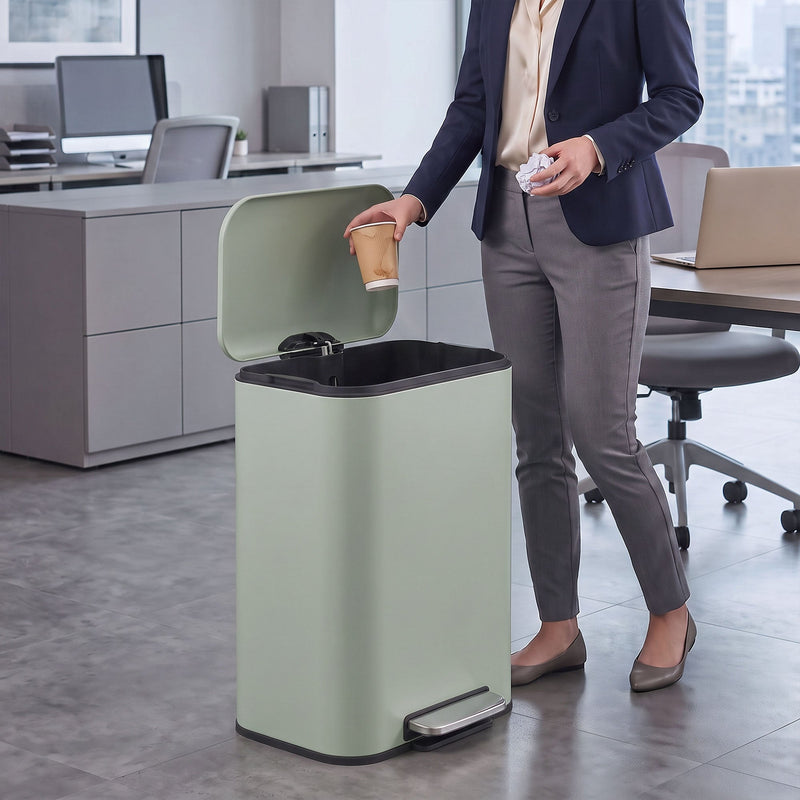 Woman in an office dropping a cup into an open light green 50L pedal bin