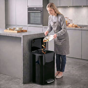 Woman scraping food into an open black 50L pedal bin in a modern kitchen