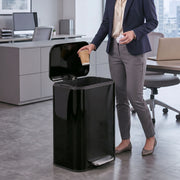 Woman in an office dropping a cup into an open black 50L pedal bin