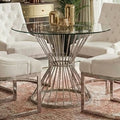 Clear glass round dining table with silver hourglass base in a dining room setting