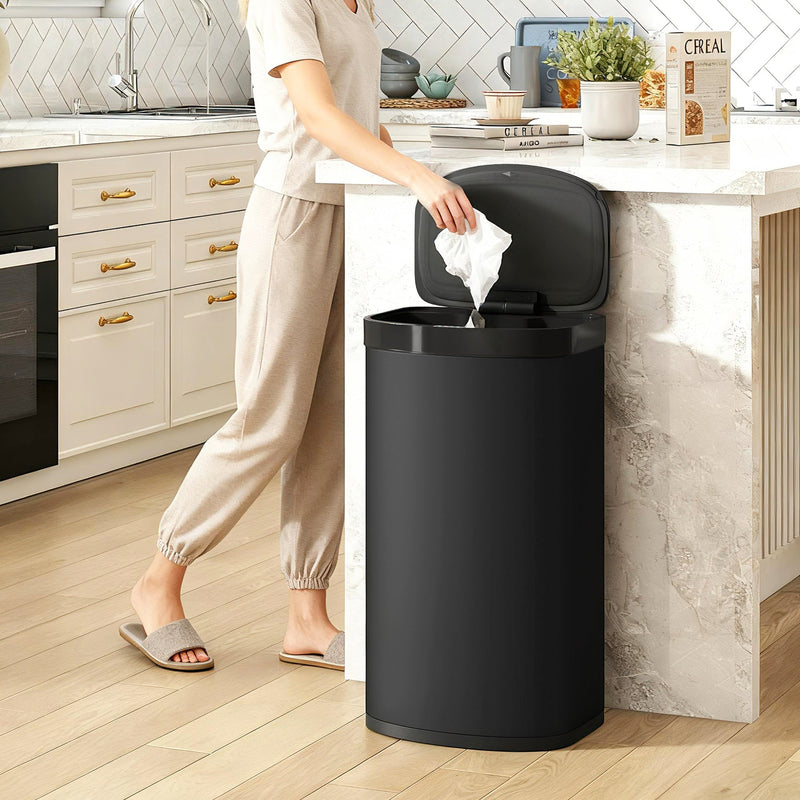 Person dropping a tissue into the open HOMCOM sensor bin in a modern kitchen