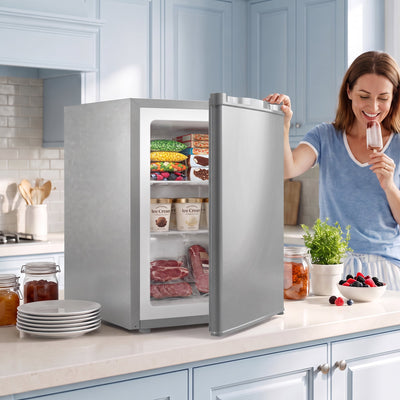 Grey mini freezer on a kitchen worktop with the door open and frozen food stacked inside