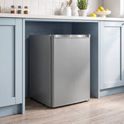 Grey mini freezer set under a kitchen counter between blue cabinets
