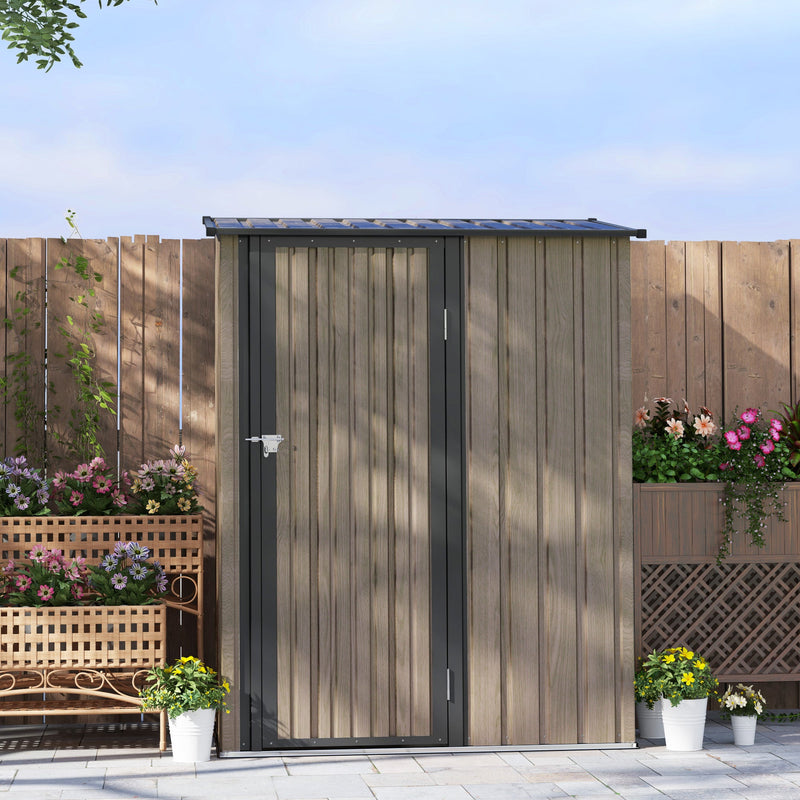 Closed light grey shed against a wooden fence with planters and flowers around it