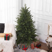 Green Christmas tree in a bright room beside an armchair and wrapped gifts