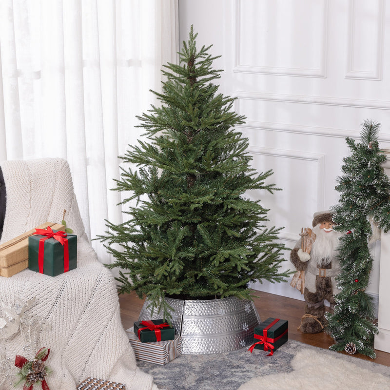 Green Christmas tree in a silver tree skirt in a bright room with gifts and a garland