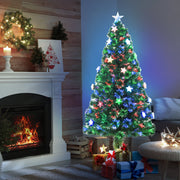 Tree glowing in front of a fireplace with a wreath and gifts