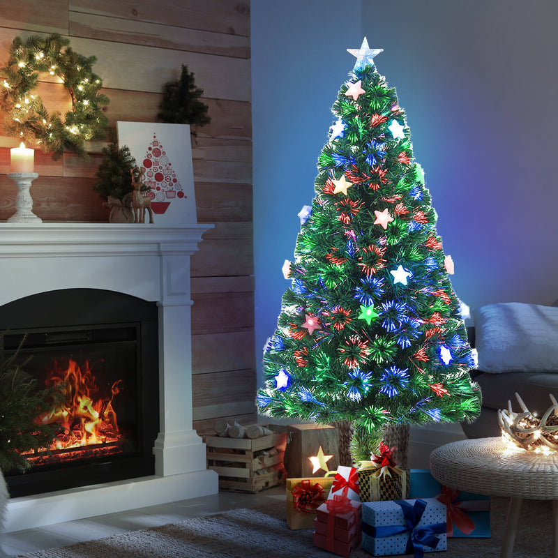 Tree glowing in front of a fireplace with a wreath and gifts