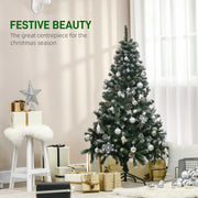 Snow flocked Christmas tree dressed with silver baubles beside gifts and a white stool