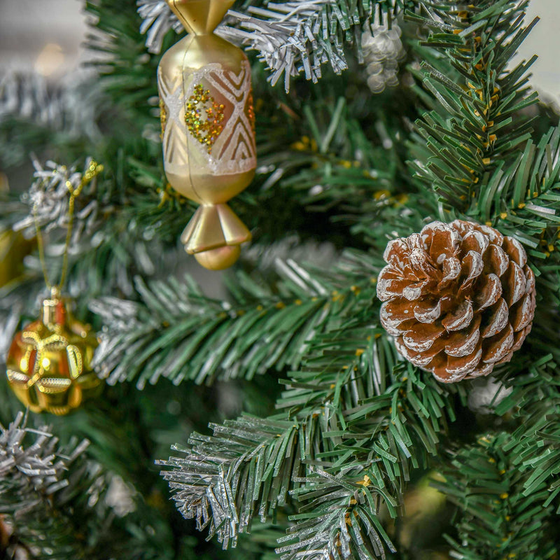 Close-up of a pine cone and gold ornaments on snow-flecked branches
