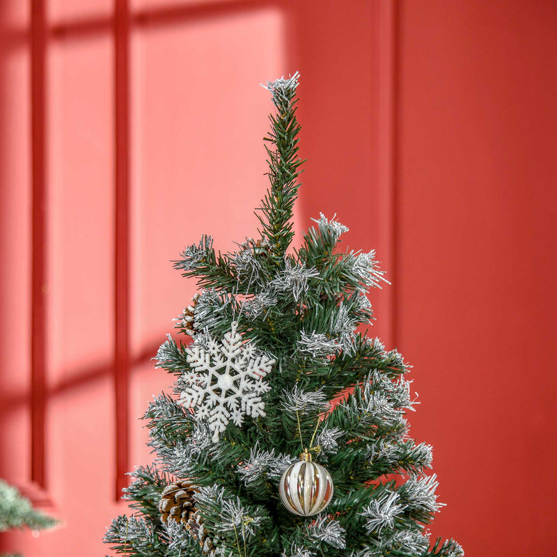 Top section of the snow flocked tree against a red wall with a snowflake hanging on it
